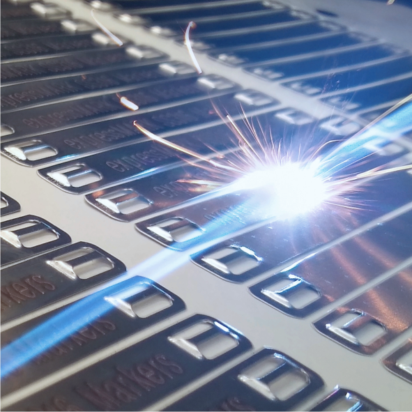 a close-up of stainless steel tie-on cable markers in the process of being laser engraved